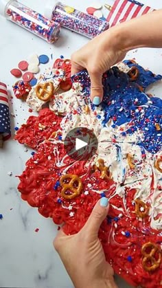 someone decorating an american flag cake with pretzels and sprinkles