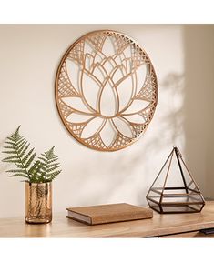 a wooden table topped with a plant and a metal circular wall hanging on the wall