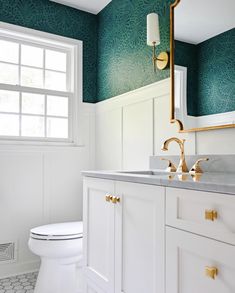 a white toilet sitting under a bathroom mirror next to a sink in a room with green walls