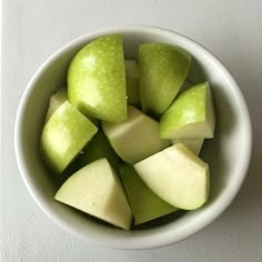 a white bowl filled with sliced apples on top of a table