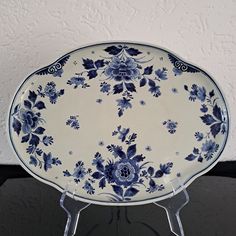 a blue and white plate sitting on top of a glass stand next to a wall