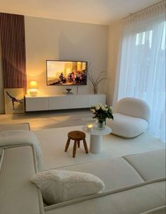 a living room filled with white furniture and a flat screen tv mounted on the wall