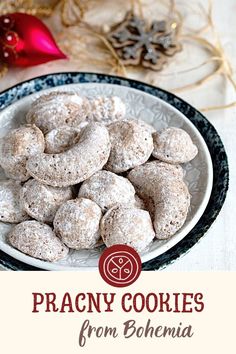 a white plate topped with cookies covered in powdered sugar next to a red christmas ornament