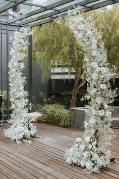 an outdoor ceremony with white flowers and greenery on the ground in front of it