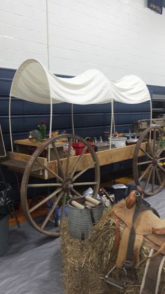 an old fashioned wagon with hay and other things on it's sides in a building