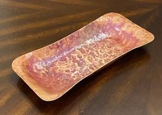 a brown and pink plate sitting on top of a wooden table