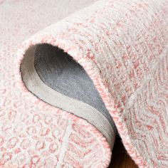 a close up of a pink and white rug on a wooden floor with a hole in the middle