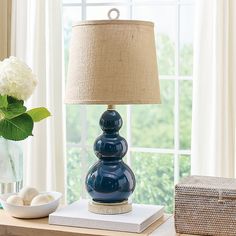 a blue lamp sitting on top of a table next to a vase with white flowers