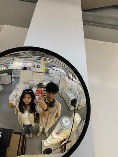 a man and woman taking a selfie in a mirror at an electronics store with their cell phones