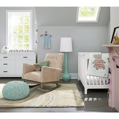 a baby's room with a rocking chair, crib and dresser in it