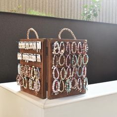 two brown bags with bracelets on them are sitting on a white shelf in front of a black wall