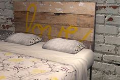 the bed is made up with white sheets and yellow letters painted on the headboard