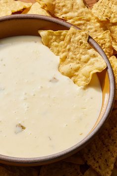 a bowl filled with white sauce surrounded by tortilla chips