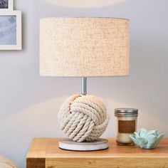 a rope ball lamp on a table next to a jar of sea salt and a candle