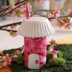 a pink and white lamp on top of a table next to a tree with flowers