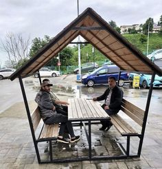 two men sitting at a picnic table in the rain