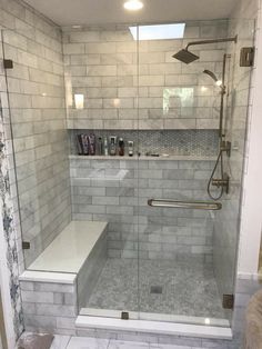 a walk in shower sitting next to a white tiled wall and floor with a bench