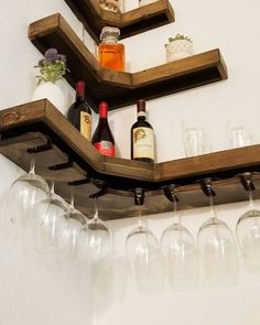 wine glasses and liquor bottles are lined up on a shelf with wooden shelves above them