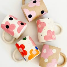 four coffee mugs with hearts painted on them sitting next to each other in different shapes and sizes