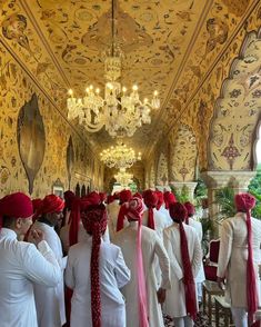 men in white and red turbans are lined up at the end of a hall