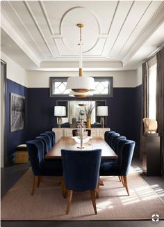 a dining room table with blue chairs and a chandelier hanging from the ceiling