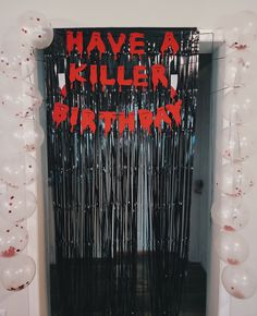 an entrance to a party with balloons and streamers in the shape of letters that read have a killer birthday