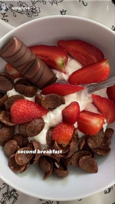 a bowl filled with strawberries, chocolate chips and yogurt next to a spoon