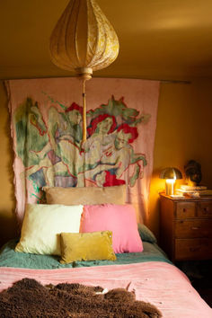 a bed with pillows and blankets on top of it in a bedroom next to a lamp