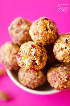 a white bowl filled with fruit and oatmeal balls on top of a pink surface