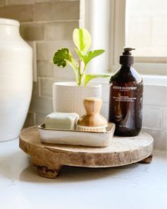 a white vase sitting on top of a counter next to a wooden tray with soap and lotion