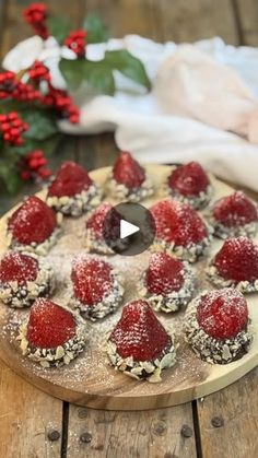 a wooden board topped with lots of desserts covered in powdered sugar and strawberries