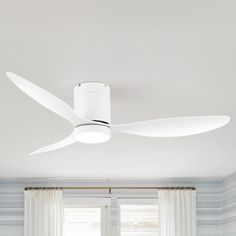 a white ceiling fan mounted above a bed in a room with blue walls and curtains