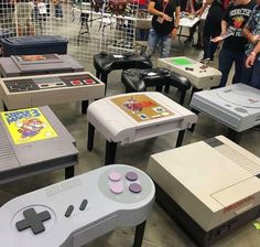 several video game consoles and tables with people standing around them