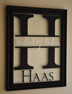 a black and white framed sign with the word haas written in cursive letters