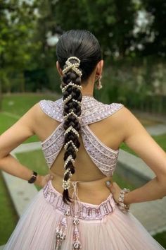 a woman wearing a pink dress with two braids in her hair, standing outside