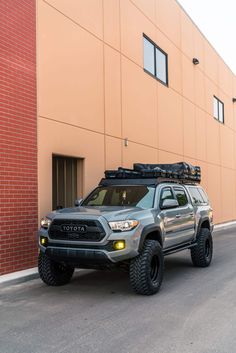 a gray toyota truck parked in front of a building with a roof rack on it's flatbed