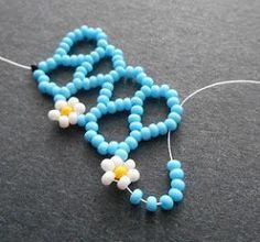 a beaded necklace with blue beads and a white flower on the end is sitting on a black surface