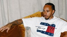 a man sitting on a couch wearing a tommy jeans shirt