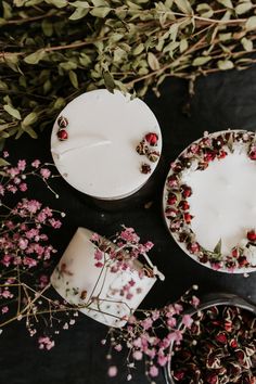 three small cakes with flowers on them sitting next to each other in front of some plants