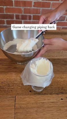 two hands are using a spoon to mix batter into a mixing bowl on a wooden table