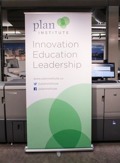 a sign that says plan institute innovation education leadership in front of some printer machines