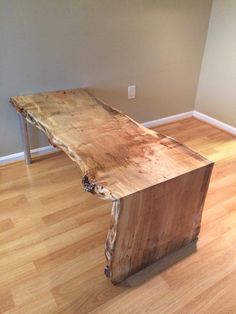 a wooden table sitting on top of a hard wood floor next to a white wall