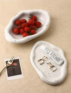 two bowls with tomatoes in them on a table next to a fork and small photo