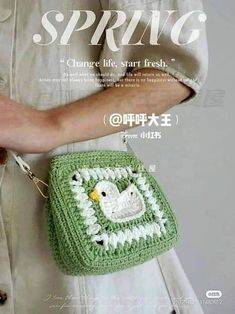 a woman holding a green crocheted purse with a white bird on it