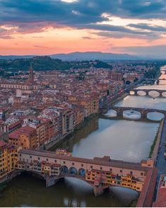 an aerial view of a city with bridges and buildings in the foreground at sunset