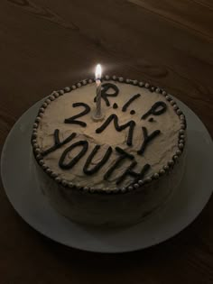 a birthday cake with the words rip my youth written on it and a lit candle