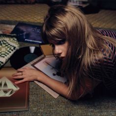 a woman laying on the floor next to a record player and other items in front of her