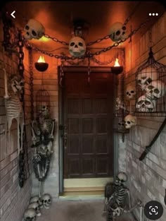 two skeleton statues sitting in front of a door decorated with halloween lights and hanging from the ceiling