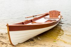 a small boat sitting on top of a sandy beach next to the water's edge