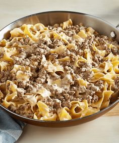 a pan full of pasta with meat and cheese in it on a wooden counter top